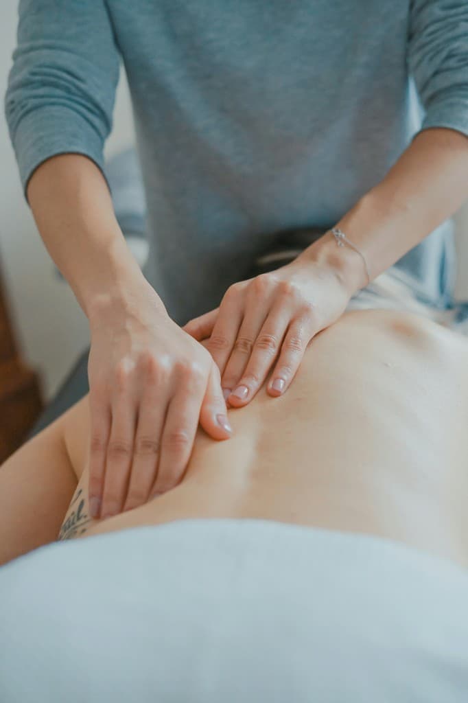 Registered Massage Therapist working with careful hand pressure along a client's lower back