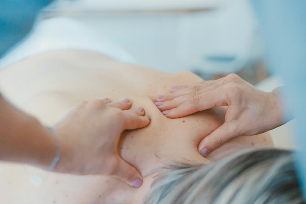 Registered Massage Therapist easing tension in a client's shoulders during a calm treatment session